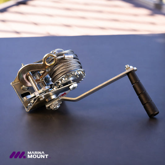 Manual ratcheting winch with coiled steel cable, metal hook, and black hand grip